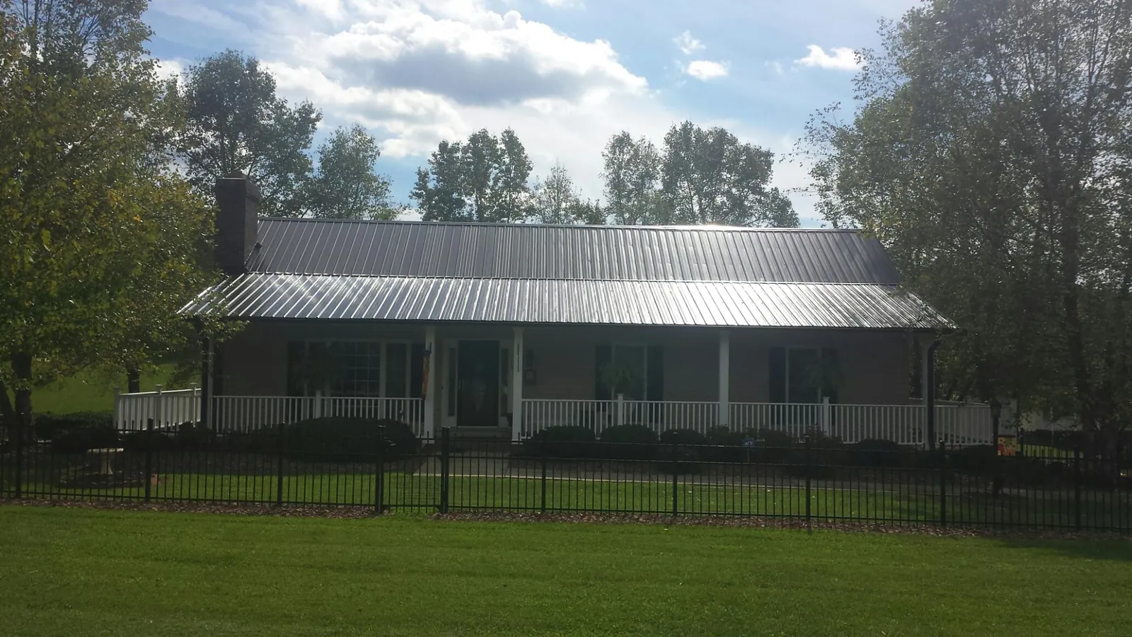 Gray metal roof on a brick ranch with a full width front porch — Gutter Guard Installation work by our crew in Fayetteville